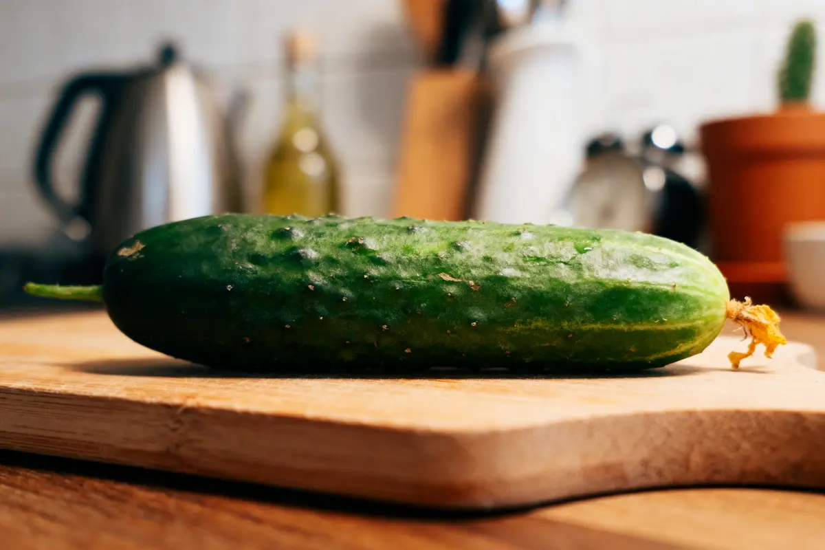 Concombre frais sur planche à découper en bois dans une cuisine moderne.