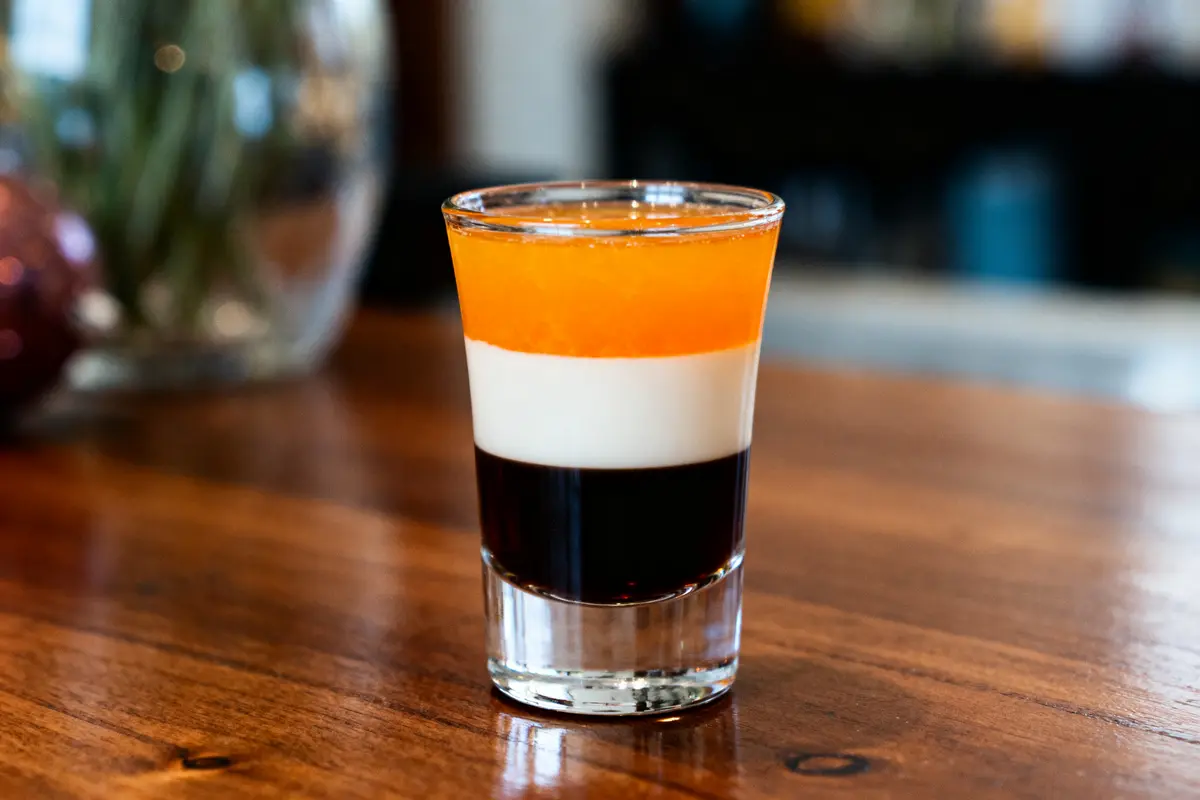Verre de B52 drink shot tricolore posé sur un comptoir en bois