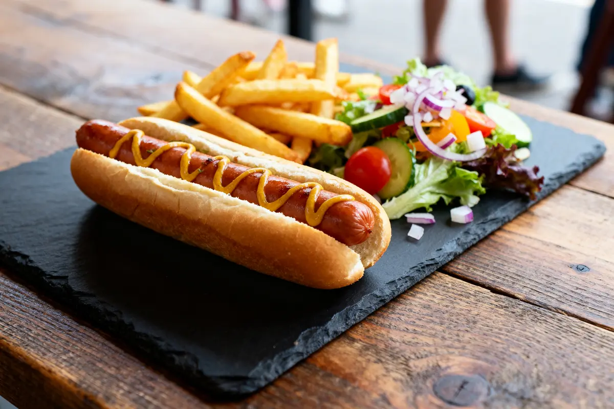 Hot dog avec moutarde, accompagné de frites et salade, un parfait accompagnement pour hot dog
