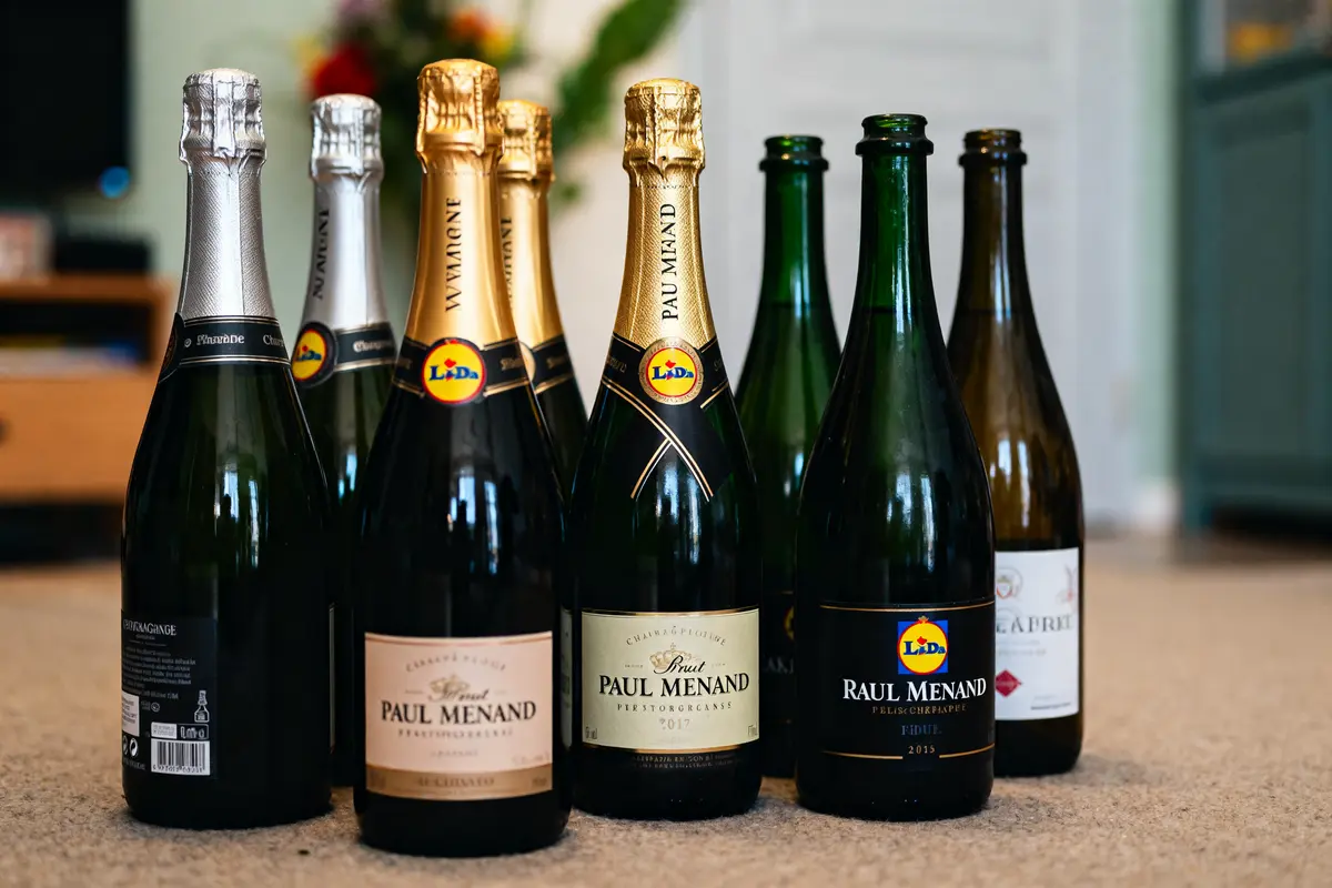 Bouteilles de champagne Lidl alignées sur un sol beige en arrière-plan flou
