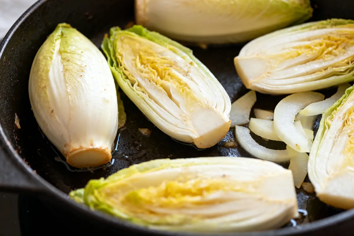 Endives et oignons préparés pour la cuisson des endives en cocotte-minute dans une poêle