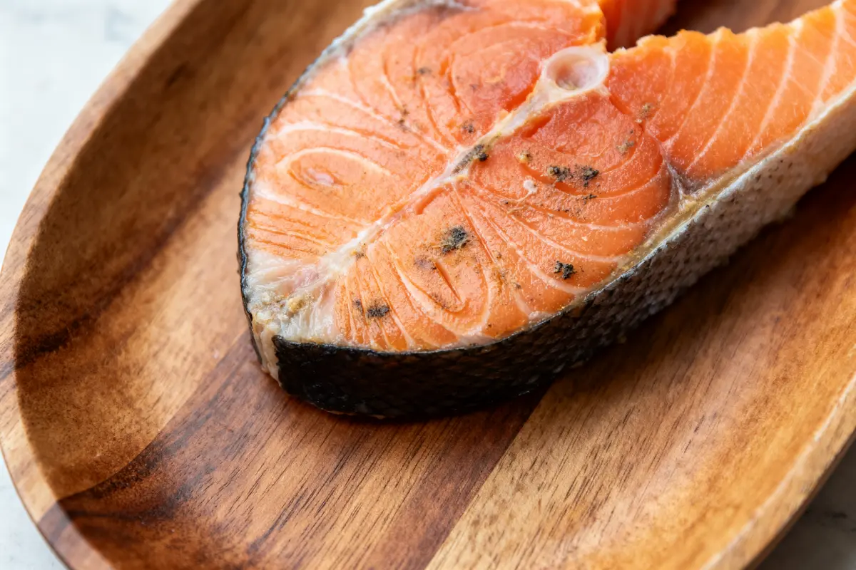 Tranche de saumon cru posée sur une planche en bois, listeria saumon possible.